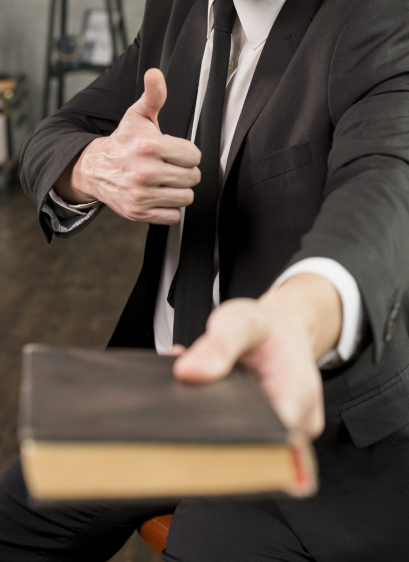 satisfied-businessman-giving-book-showing-thumb-up